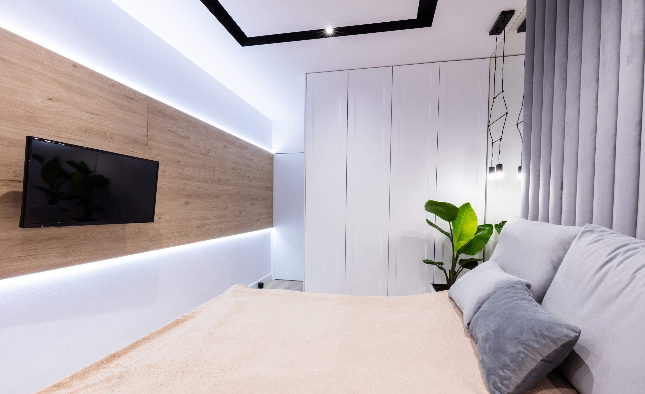Moderne slaapkamer met LED-verlichting, houten wandafwerking en ingebouwde kast, gerealiseerd door JRC Afbouw.