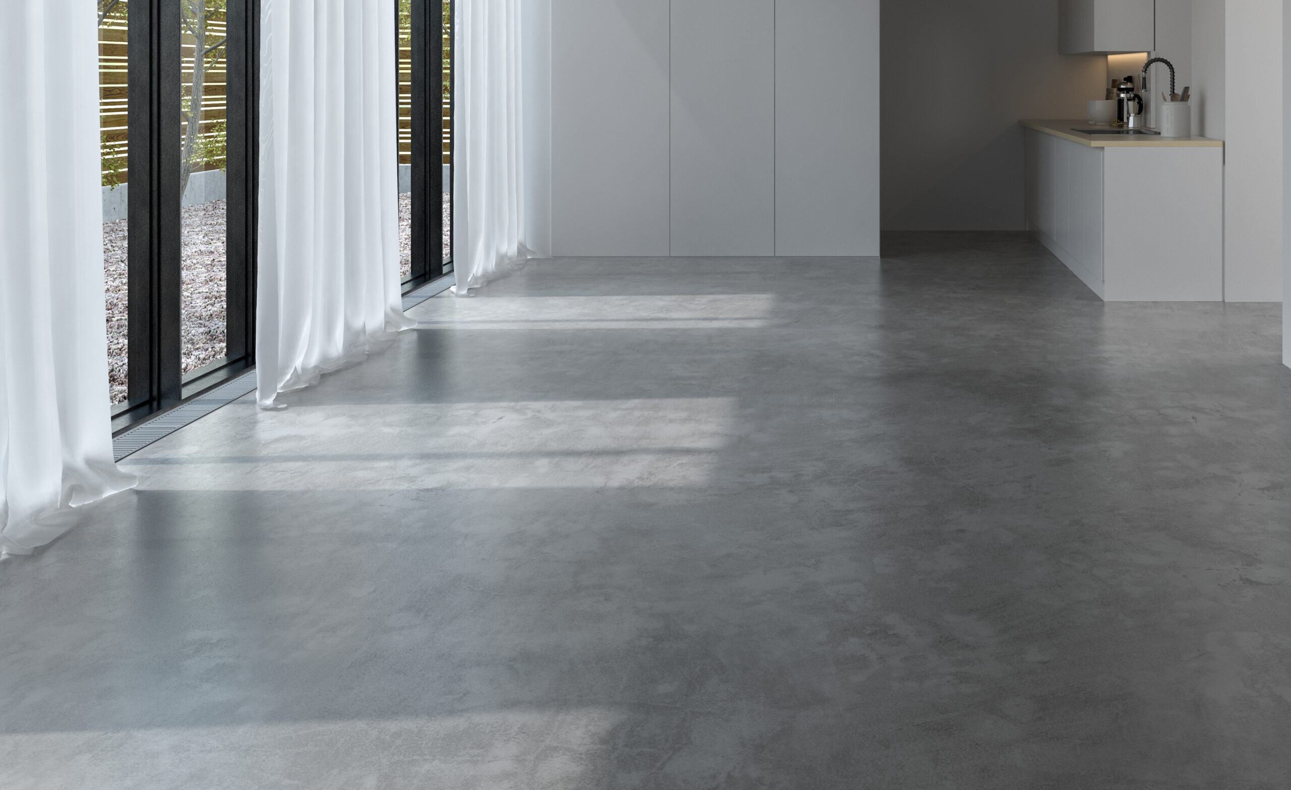 Grijze gietvloer in minimalistische ruimte met veel lichtinval, geplaatst door JRC Afbouw & Afwerking.