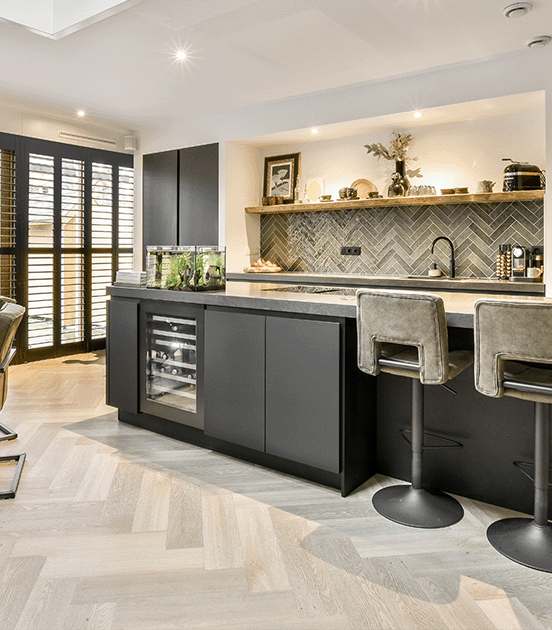 Een moderne keuken met een luxe visgraatvloer, donkere keukenkasten en een stijlvolle ingebouwde nis, gerealiseerd door JRC Afbouw