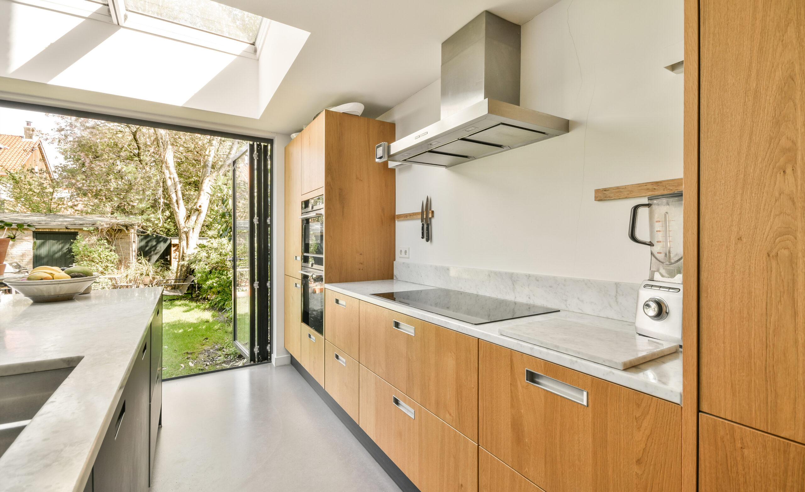 Moderne keuken met openslaande deuren naar de tuin en houten keukenkasten, gerealiseerd door JRC Afbouw.