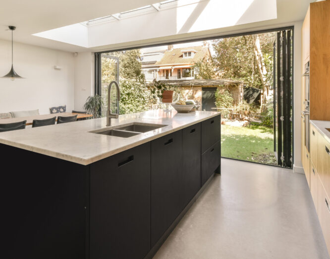 Moderne keuken met donker keukenblok, marmeren aanrechtblad en stijlvolle ingebouwde apparatuur, afgewerkt door JRC Afbouw.