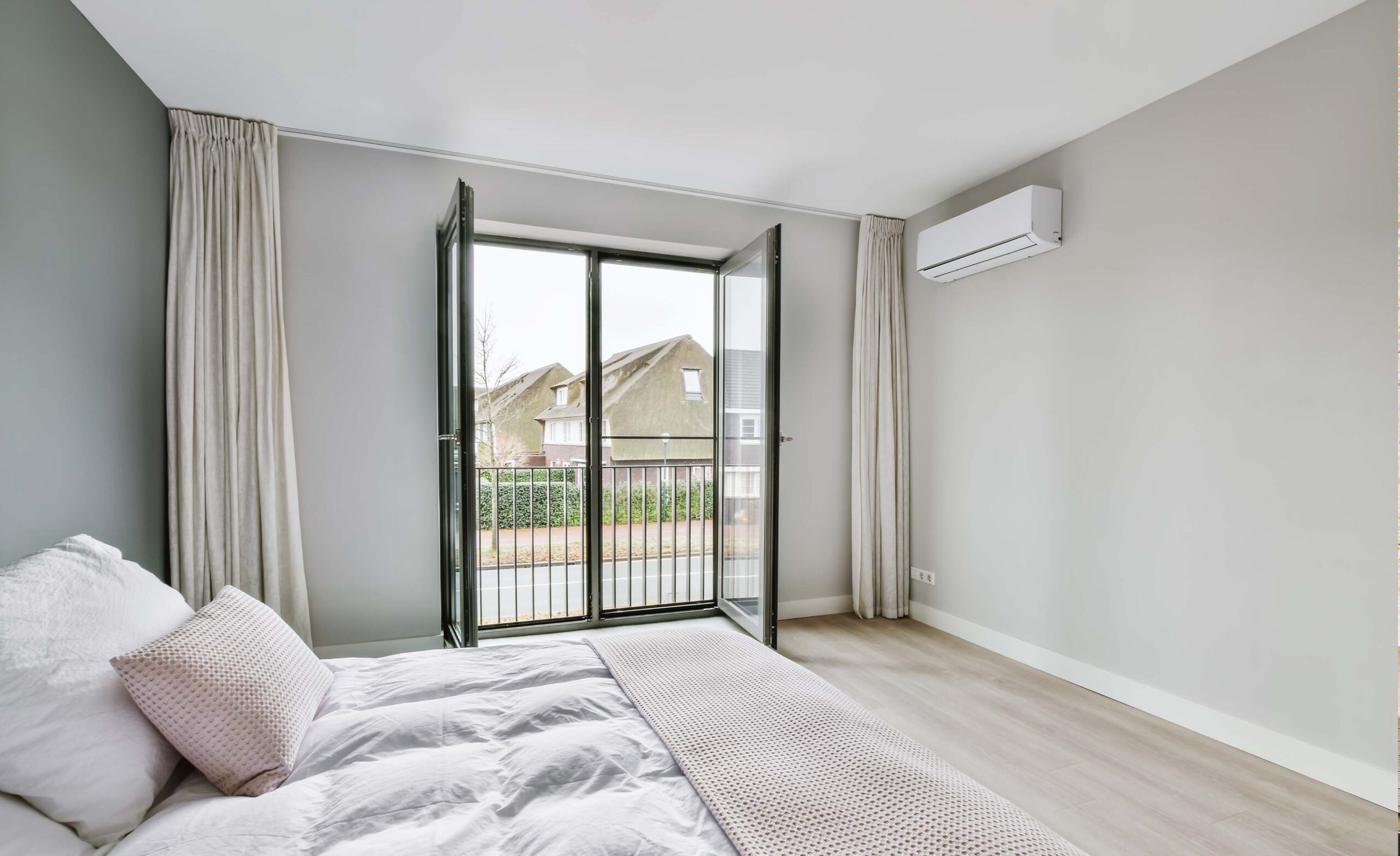 Slaapkamer met airconditioning en grote ramen, afgewerkt door JRC Afbouw.