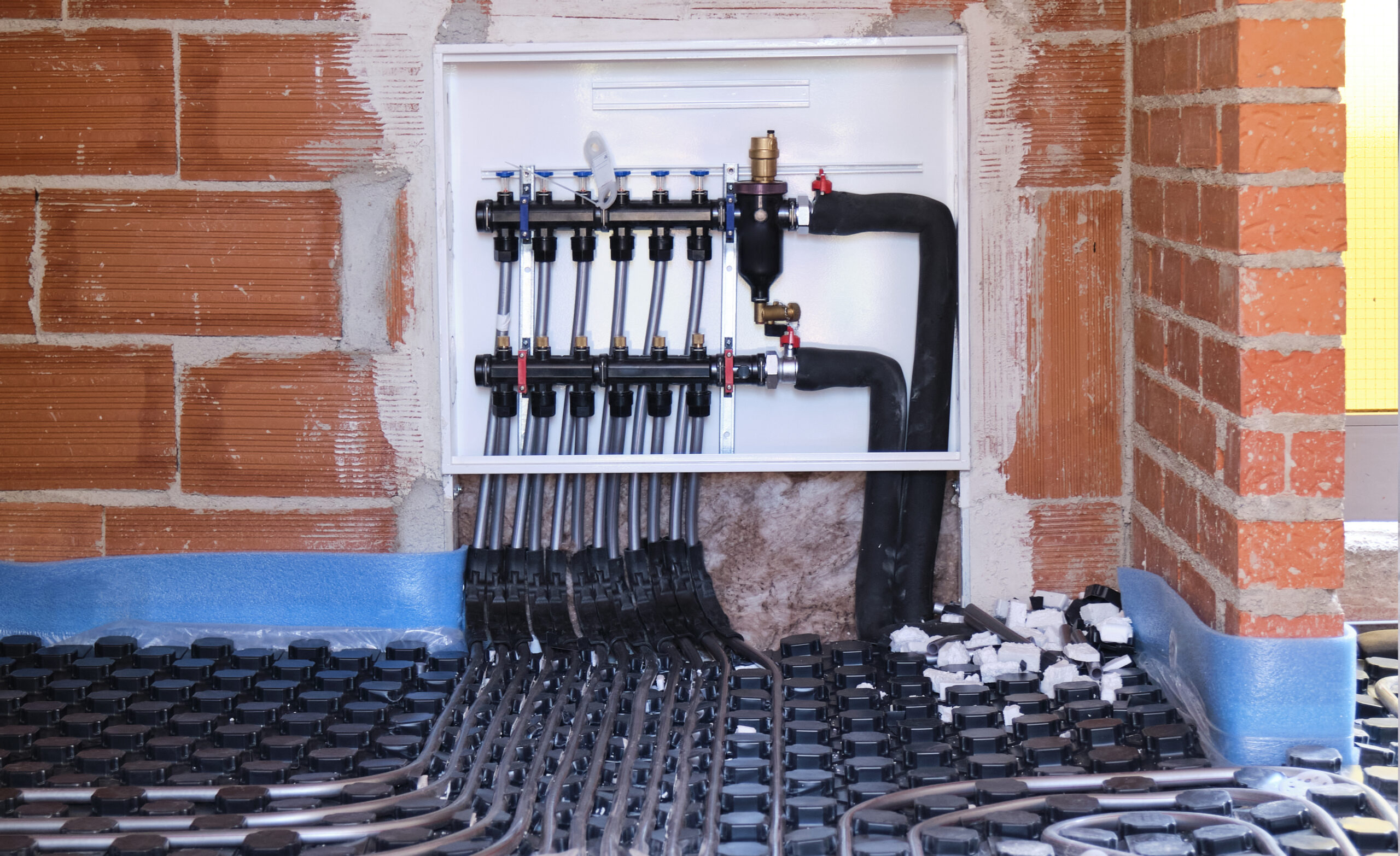 Vloerverwarmingsverdeler geïnstalleerd door JRC Afbouw voor een efficiënte en gelijkmatige warmteverdeling.