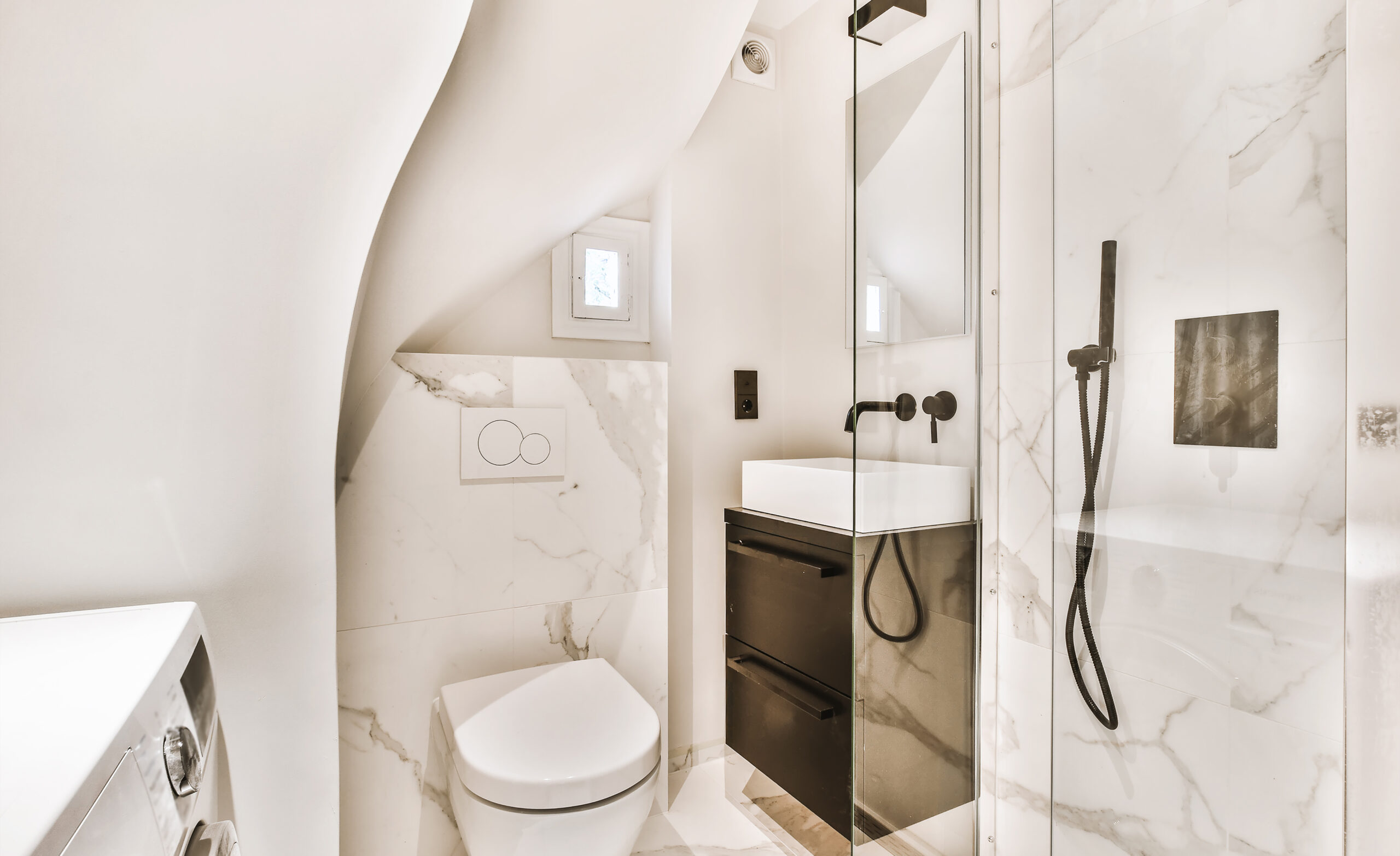Compacte badkamer met witte marmeren tegels en zwarte kraan gerealiseerd door JRC Afbouw.